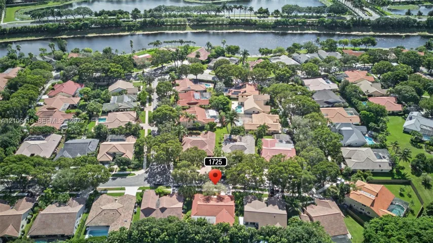 Aerial perspective of residential neighborhood featuring mature canopy trees, paved street grid, and bordering waterway