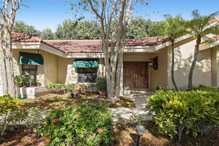 Stucco exterior featuring a clay tile roof, double-door entry, and decorative canvas window awnings