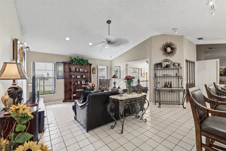 Living area featuring vaulted ceilings, ceramic tile flooring, built-in shelving, and a central ceiling fan