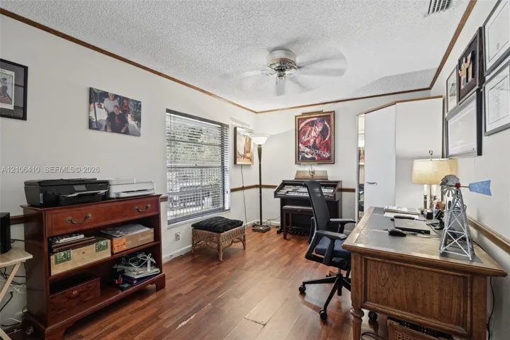 Wood-finish flooring, ceiling fan with integrated lighting, horizontal window blinds, and chair rail molding