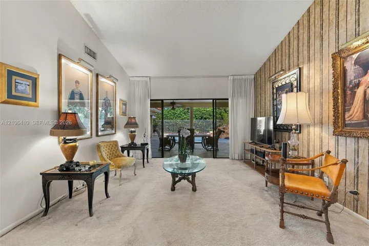 Living space featuring vaulted ceilings, floor-to-ceiling sliding glass doors, and decorative wall covering