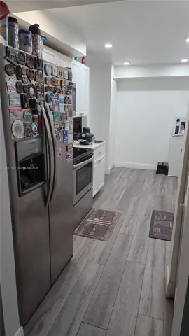Kitchen featuring stainless steel appliances, white cabinetry, and wood-finish flooring with recessed lighting