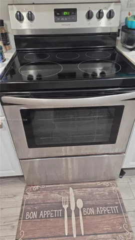 Stainless steel freestanding electric range with a glass cooktop, digital control panel, and full-width oven handle
