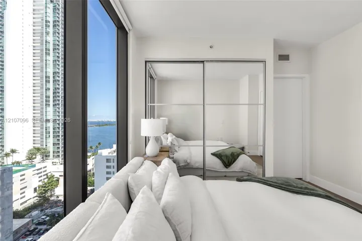 Floor-to-ceiling windows, mirrored sliding-door closet, and neutral interior finishes