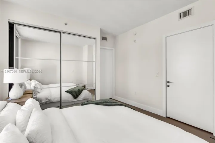 Floor-to-ceiling sliding mirrored closet doors, solid core interior door, and neutral wall finish