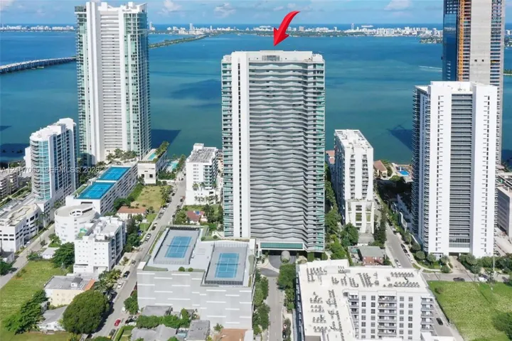 High-rise residential tower featuring a tiered glass facade, prominent balcony structures, and an elevated rooftop terrace