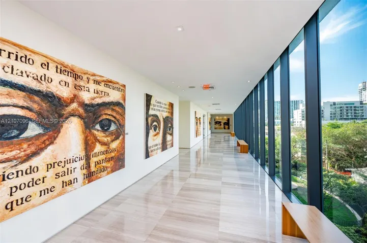 Gallery hallway featuring floor-to-ceiling windows, polished stone flooring, and recessed ceiling lighting