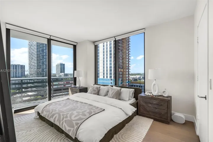 Floor-to-ceiling windows, wood-finish flooring, and metal-framed balcony railing