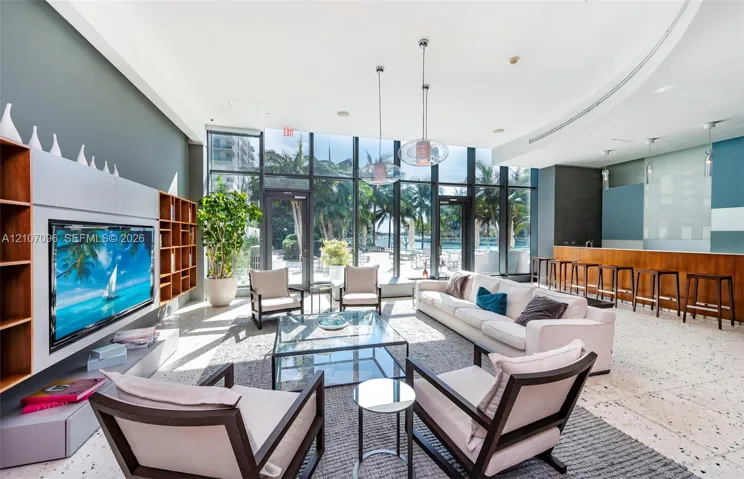 Floor-to-ceiling windows, built-in shelving, stone tile flooring, recessed ceiling lighting, and a custom bar