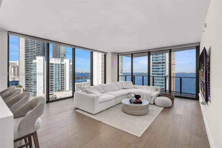Floor-to-ceiling windows, wood-finish flooring, and wraparound glass balcony railings
