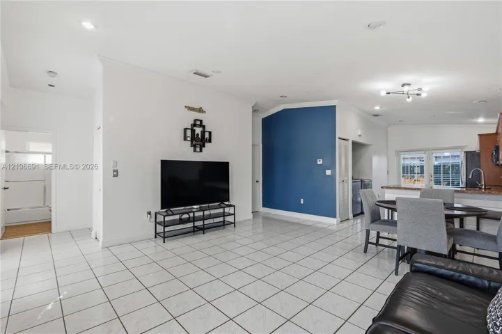 Open-concept interior featuring large-format ceramic tile flooring, vaulted ceilings, recessed lighting, and a distinct blue accent wall
