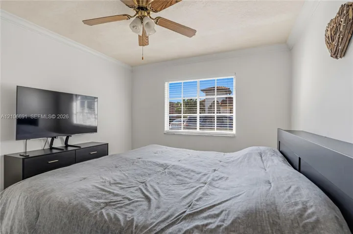 Multi-pane window with white frame, ceiling-mounted wooden blade fan with integrated light fixture, and crown molding