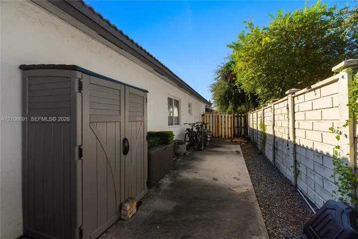 Concrete side exterior pathway featuring masonry block perimeter fencing and exterior stucco finish