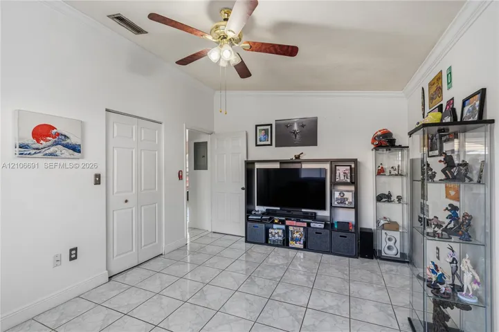Neutral-toned tile flooring, ceiling fan with integrated lighting, crown molding, and multi-panel interior doors