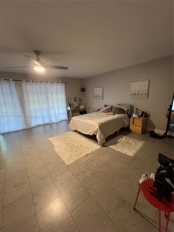 Neutral-toned ceramic tile flooring, large sliding glass door with integrated tracks, and a contemporary ceiling fan with integrated lighting