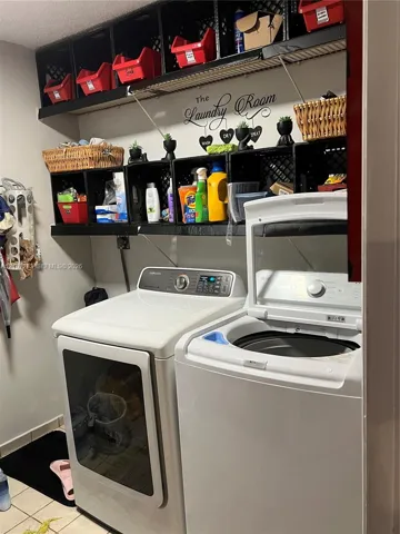 Laundry area featuring wall-mounted storage shelving and tile flooring