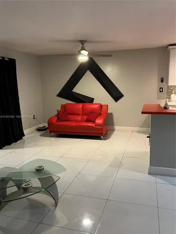Large-format tile flooring, ceiling fan with integrated lighting, and built-in counter peninsula