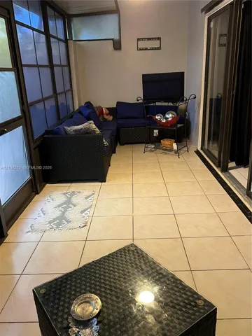 Enclosed sunroom featuring large-format tile flooring, multi-pane floor-to-ceiling windows, and sliding glass door access