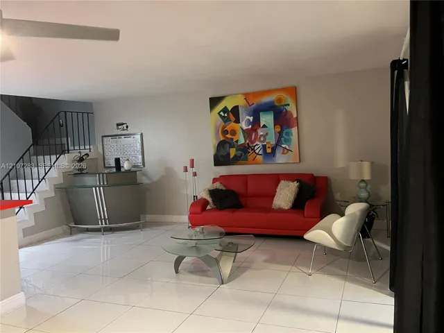Large-format tile flooring, metal staircase railing, and ceiling-mounted fan