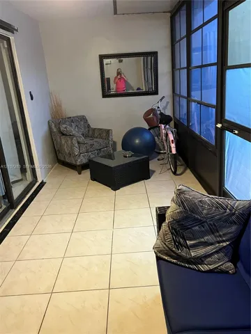 Enclosed porch featuring large-format ceramic floor tiles, multi-pane floor-to-ceiling windows with black framing, and sliding glass entry door