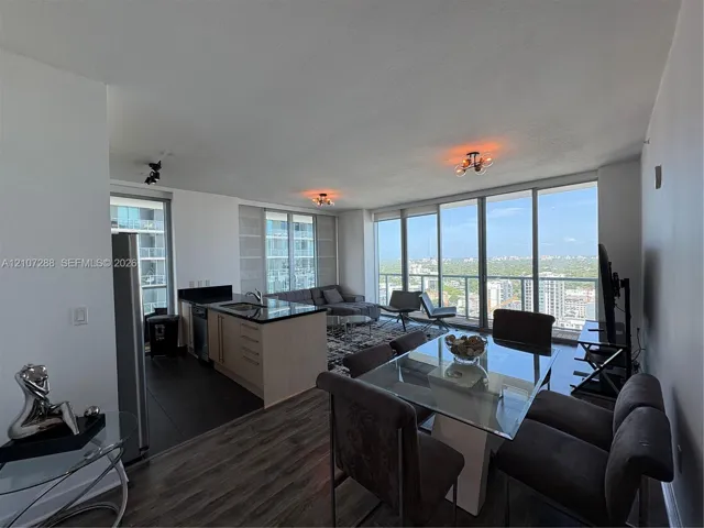 Open-concept floor plan featuring floor-to-ceiling windows, wood-finish flooring, kitchen island with stone countertops, and built-in stainless steel appliances