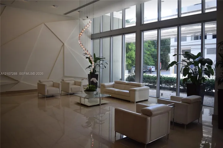 Floor-to-ceiling windows, geometric relief wall detailing, polished tile flooring, and a multi-tiered spiral pendant light