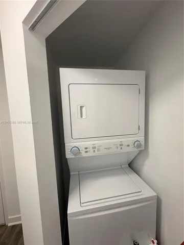 Stackable white laundry unit featuring a top-load washer and front-load dryer in a dedicated recessed closet