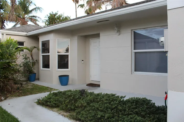 Exterior facade featuring a stucco finish, recessed entry, concrete walkway, bay windows, and horizontal siding accents