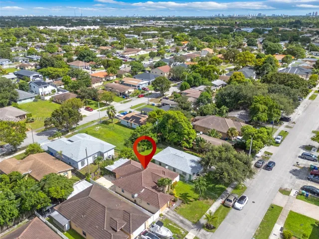 Aerial view of a residential lot featuring a concrete tile roof, attached garage, and paved driveway