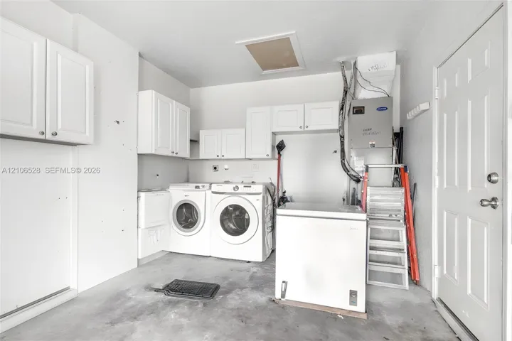 Utility area featuring wall-mounted white cabinetry, an HVAC system, and a six-panel entry door