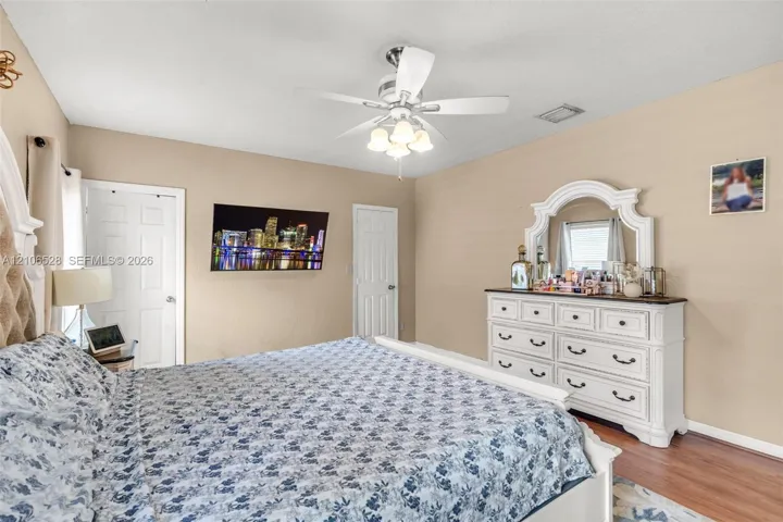 Bedroom featuring wood-finish flooring, multi-paneled interior doors, and a ceiling-mounted light fixture with a fan