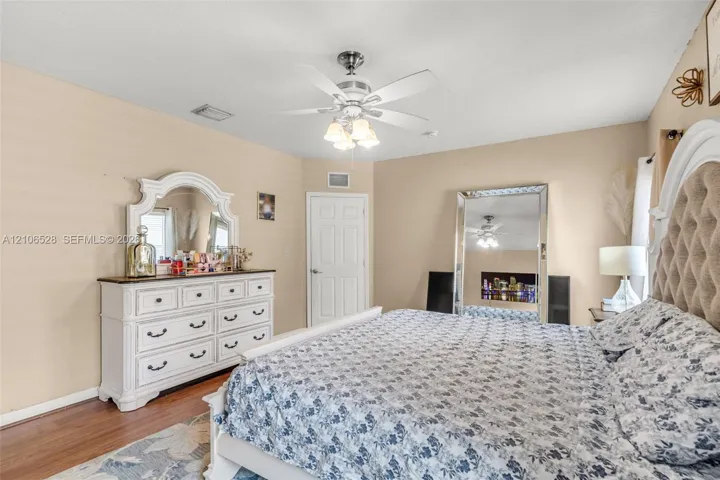 Bedroom featuring wood-finish flooring, a multi-blade ceiling fan with integrated lighting, and a neutral wall finish