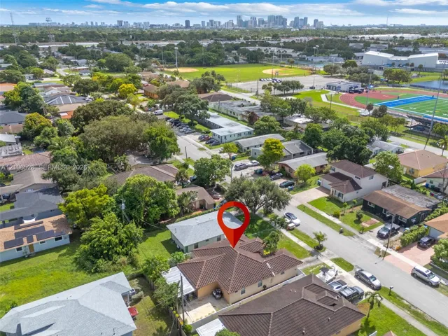 Aerial view featuring a residential property with a tiled roof, situated on a corner lot with mature landscaping