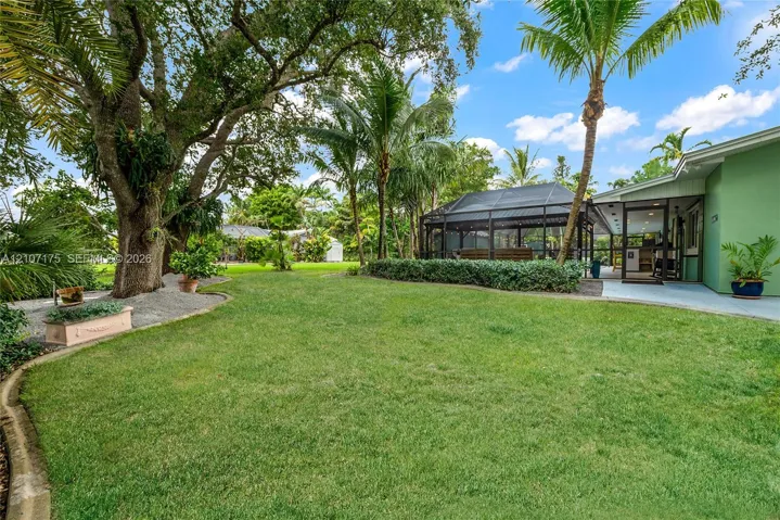 Expansive backyard featuring a manicured lawn, mature trees, and landscaped garden borders.