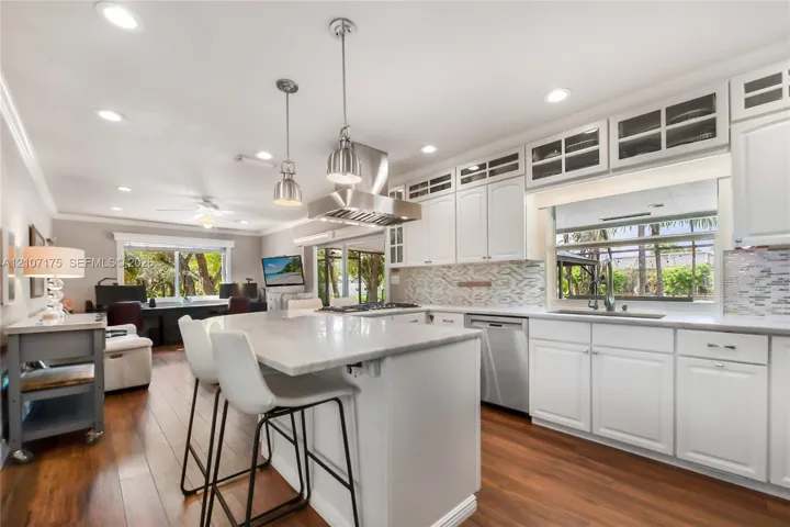 Chefs kitchen featuring white shaker-style cabinetry, industrial pendants, a central island with granite.