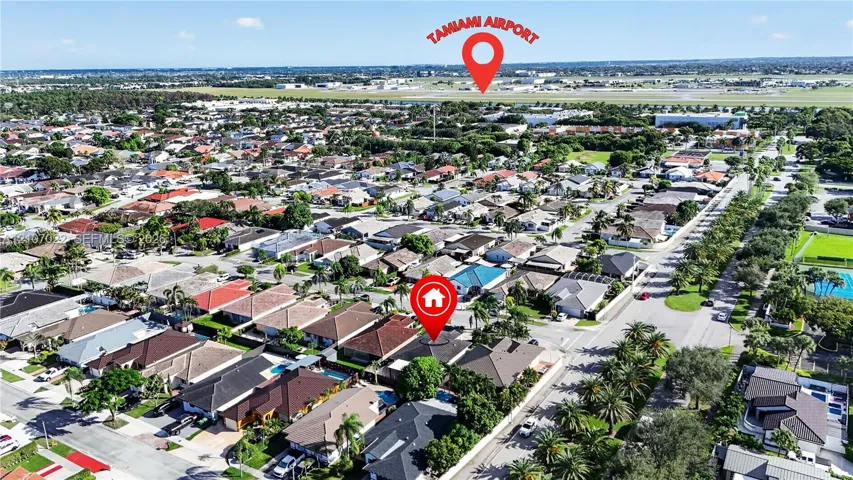 Aerial perspective of a residential neighborhood featuring paved streets, mature canopy trees, and proximity to regional aviation infrastructure