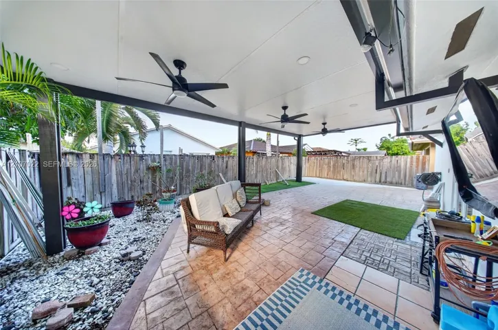 Covered patio featuring stamped concrete flooring, three ceiling fans, recessed lighting, and wooden privacy fencing