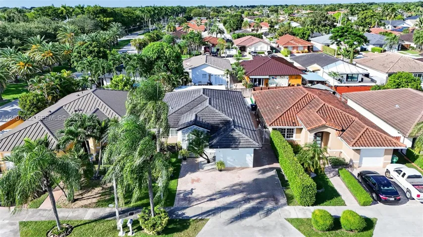 Aerial perspective of a single-story residence featuring a concrete tile roof, paved driveway, one car garage, and mature perimeter landscaping