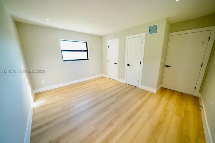 Interior room featuring wood-finish flooring, recessed lighting, neutral wall paint, and multiple interior doors with matte black hardware