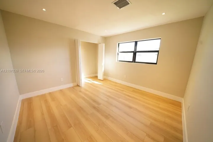 Neutral-toned interior featuring wood-finish flooring, recessed lighting, and a window with a black frame