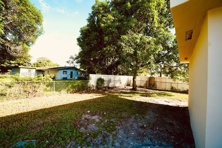 Backyard featuring a grass lawn, mature trees, and privacy fencing