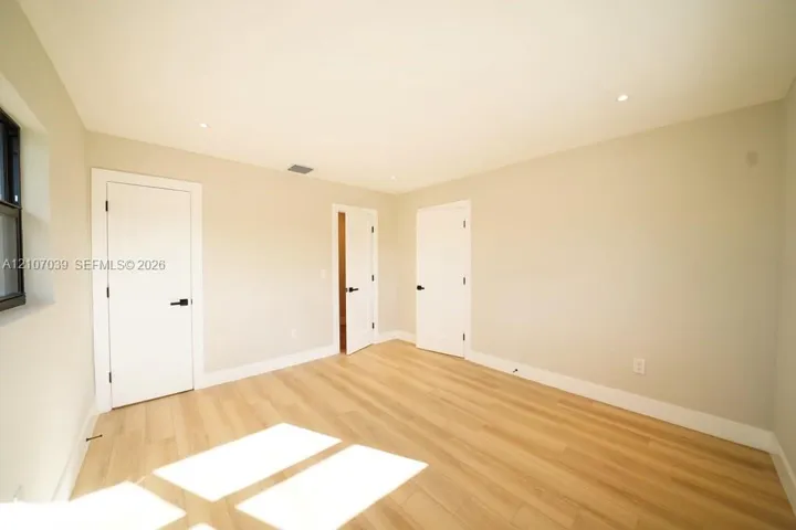 Neutral-toned walls, wood-finish flooring, recessed lighting, and white interior doors with matte black hardware