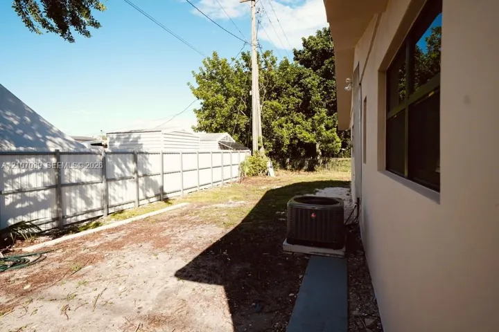 Side yard featuring a perimeter vinyl privacy fence, stucco exterior wall, and an external HVAC condenser unit