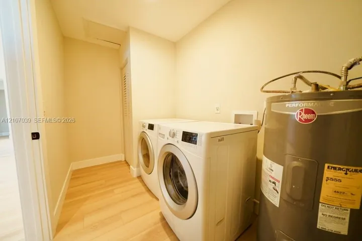 Laundry area featuring wood-finish flooring, a tank water heater, and washer and dryer hookups