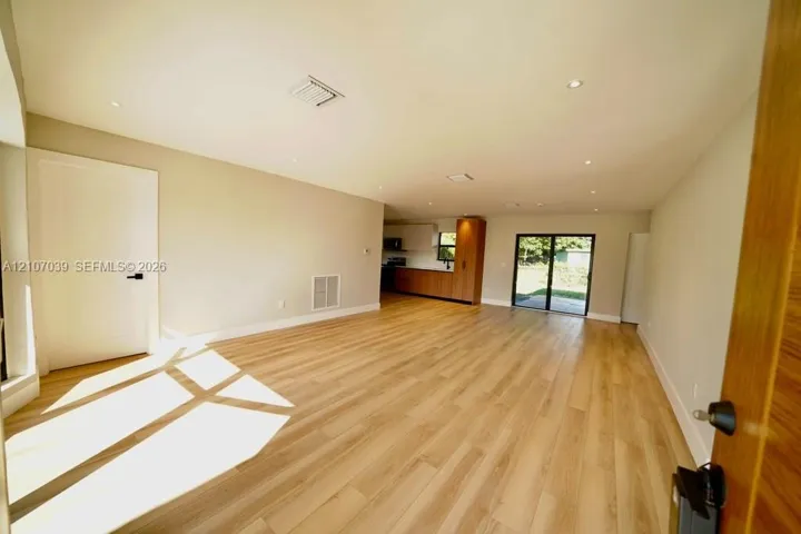 Open-concept interior featuring light wood-finish flooring, recessed lighting, and sliding glass doors
