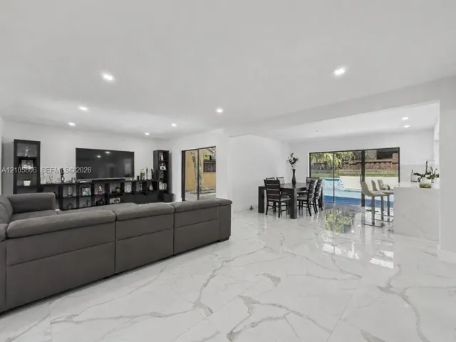 Open-concept floor plan featuring large-format veined tile flooring, recessed ceiling lighting, and sliding glass doors to the exterior