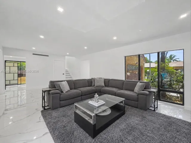 Large-format tile flooring with veining detail, recessed lighting, expansive floor-to-ceiling windows, and a black-framed glass door