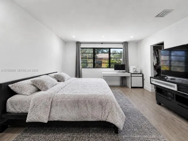 Neutral-toned room featuring wood-finish flooring, recessed lighting, and multi-pane window with dark frames