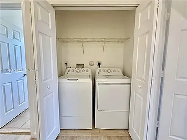 Laundry closet featuring a wire shelving rack, dual-panel folding doors, and neutral tile flooring