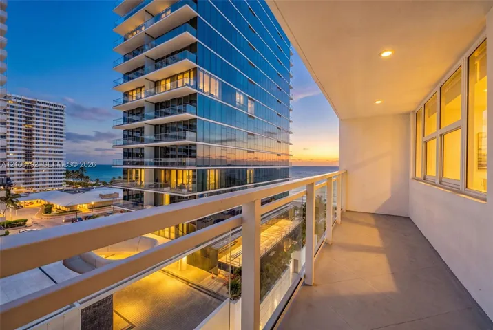 Covered balcony featuring a glass and metal railing system, recessed lighting, and tile flooring